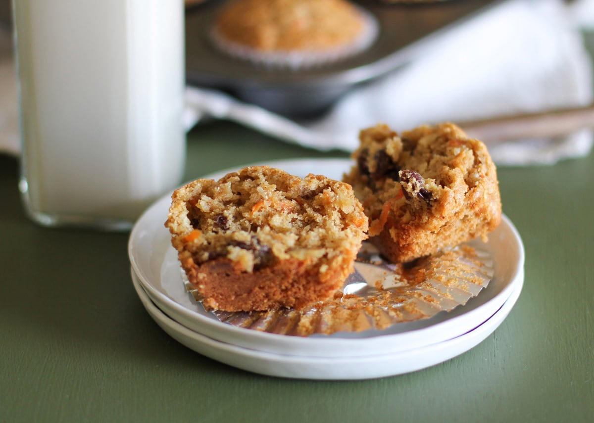 White plate with a paleo morning glory muffin sliced in half and the rest of the muffins in the background.
