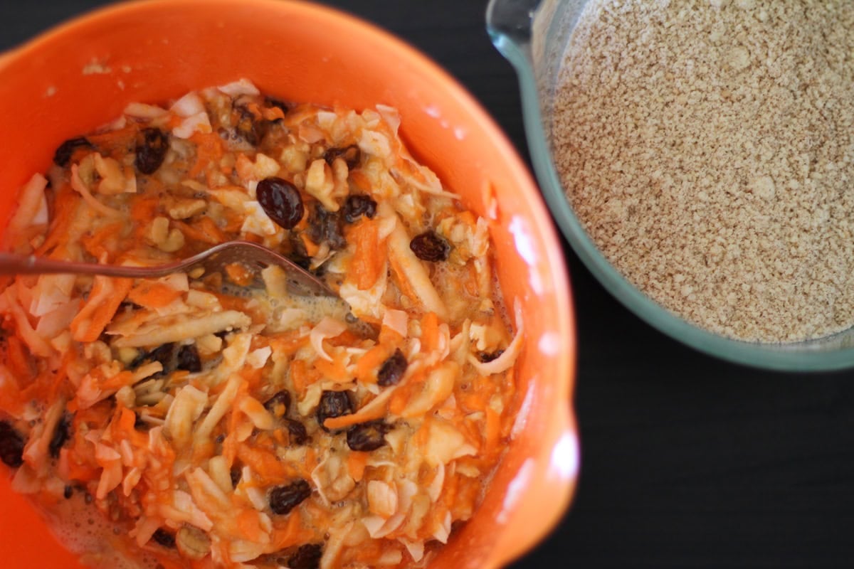 Mixing bowl with wet ingredients for paleo morning glory muffins and another bowl to the side with the dry ingredients.