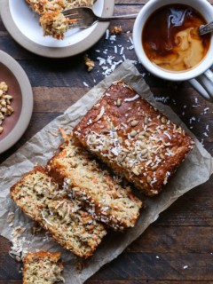 Loaf of morning glory muffin bread on a wooden background, cut into thick slices with a mug of coffee to the side.