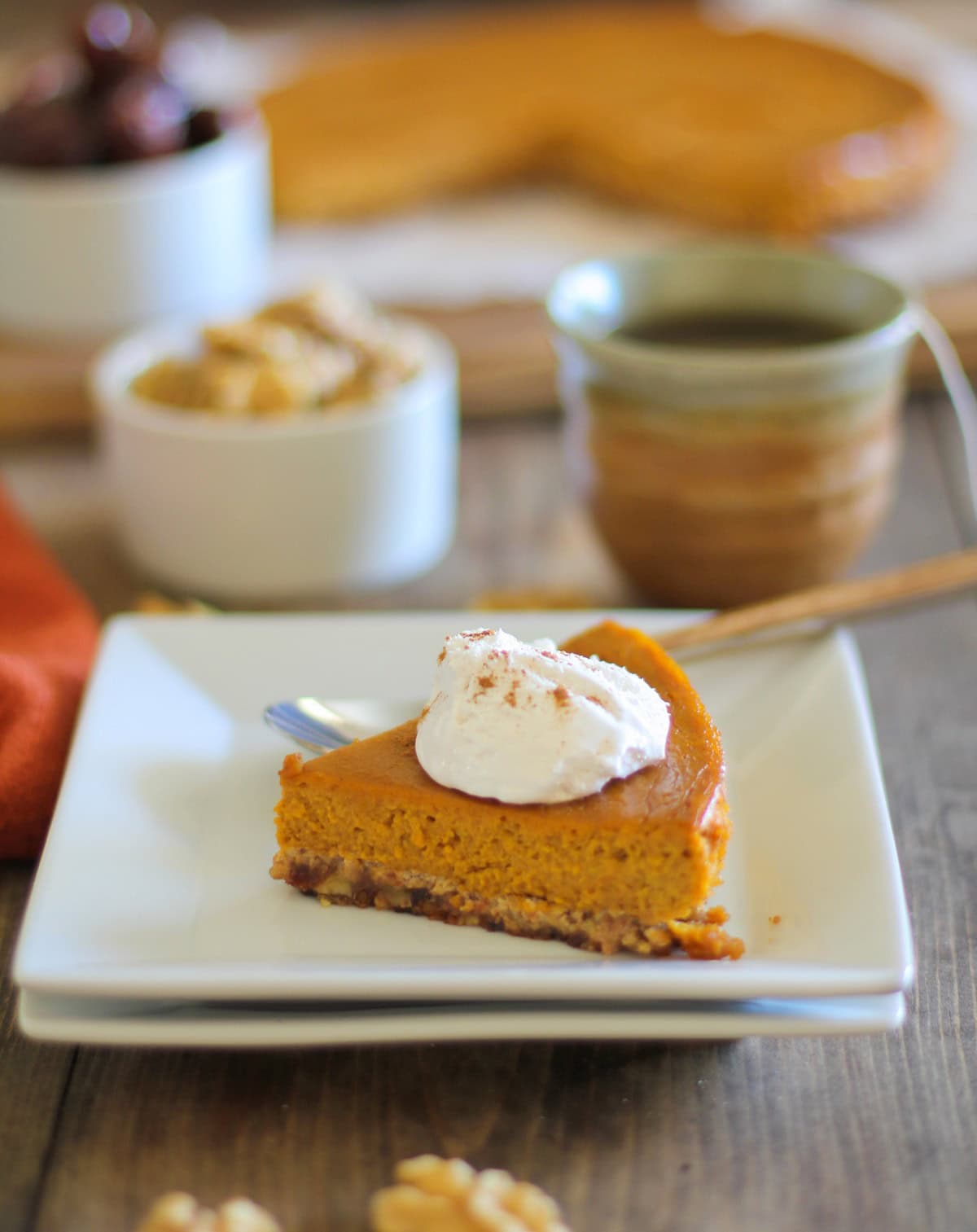 Paleo Pumpkin Pie sitting on two white plates with walnuts all around and the rest of the pie in the background
