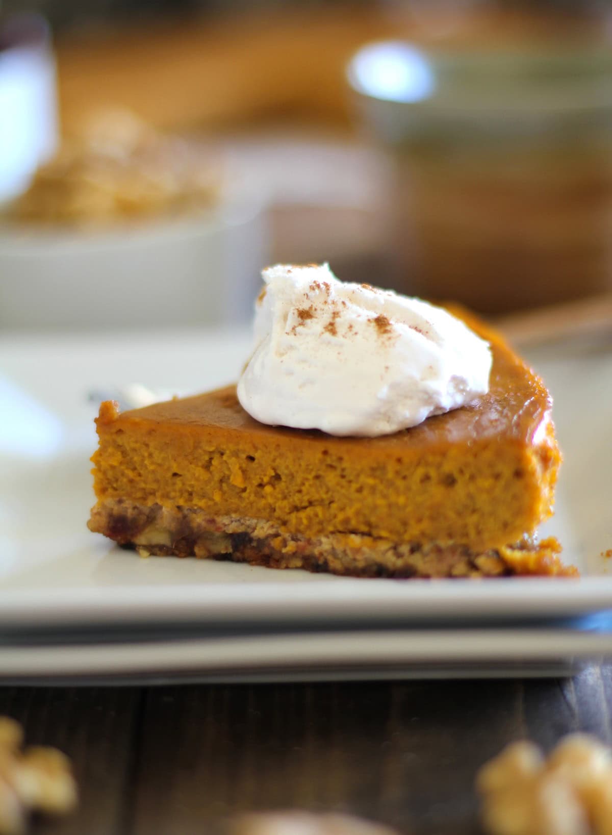 Slice of pumpkin pie sitting on two white plates with whipped cream on top.