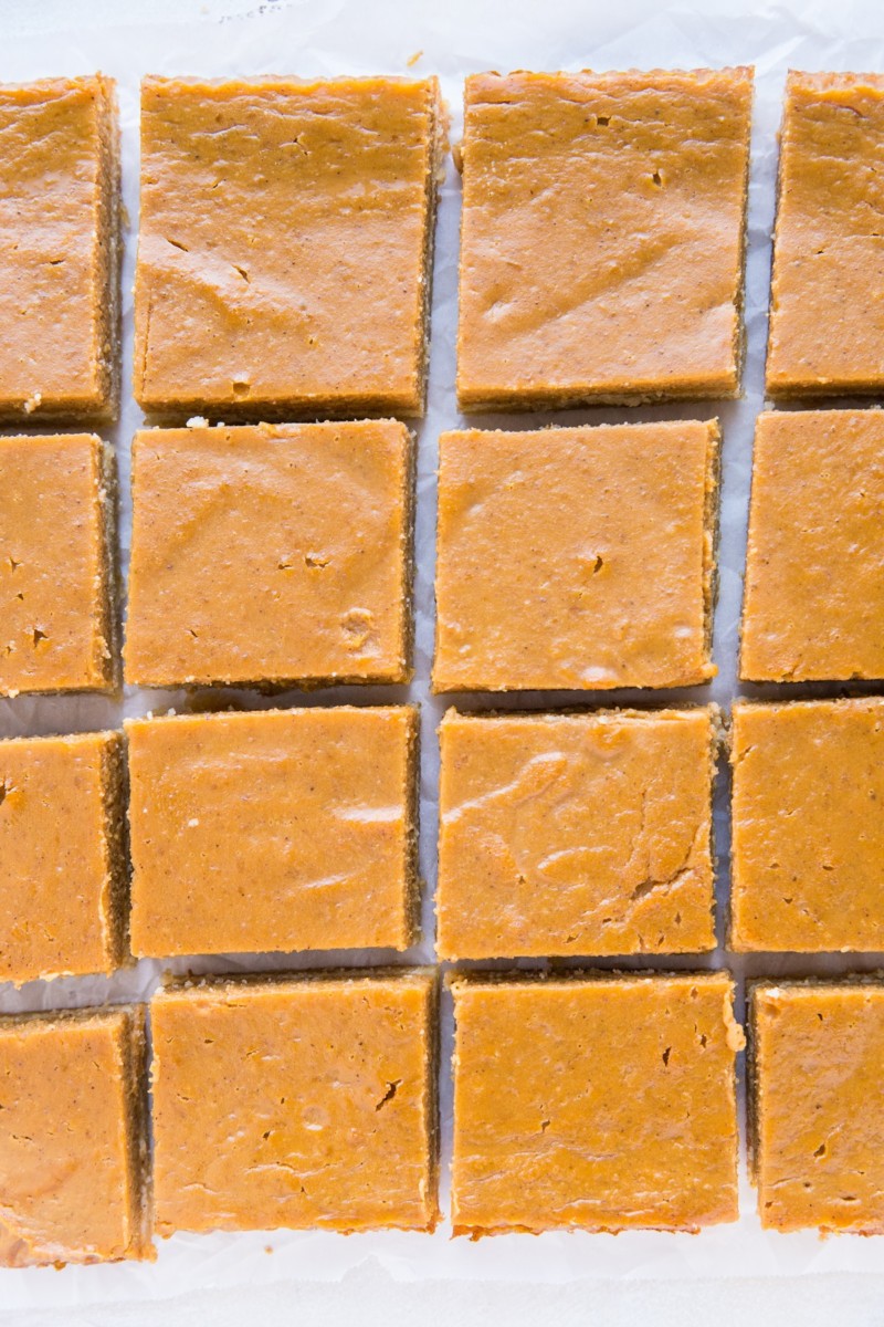 Healthy Paleo Pumpkin Pie Bars cut into individual squares on a sheet of parchment paper.