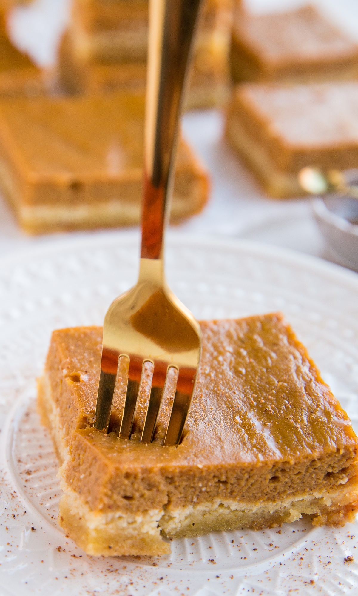 Pumpkin pie bar on a plate with a fork taking a piece of it.