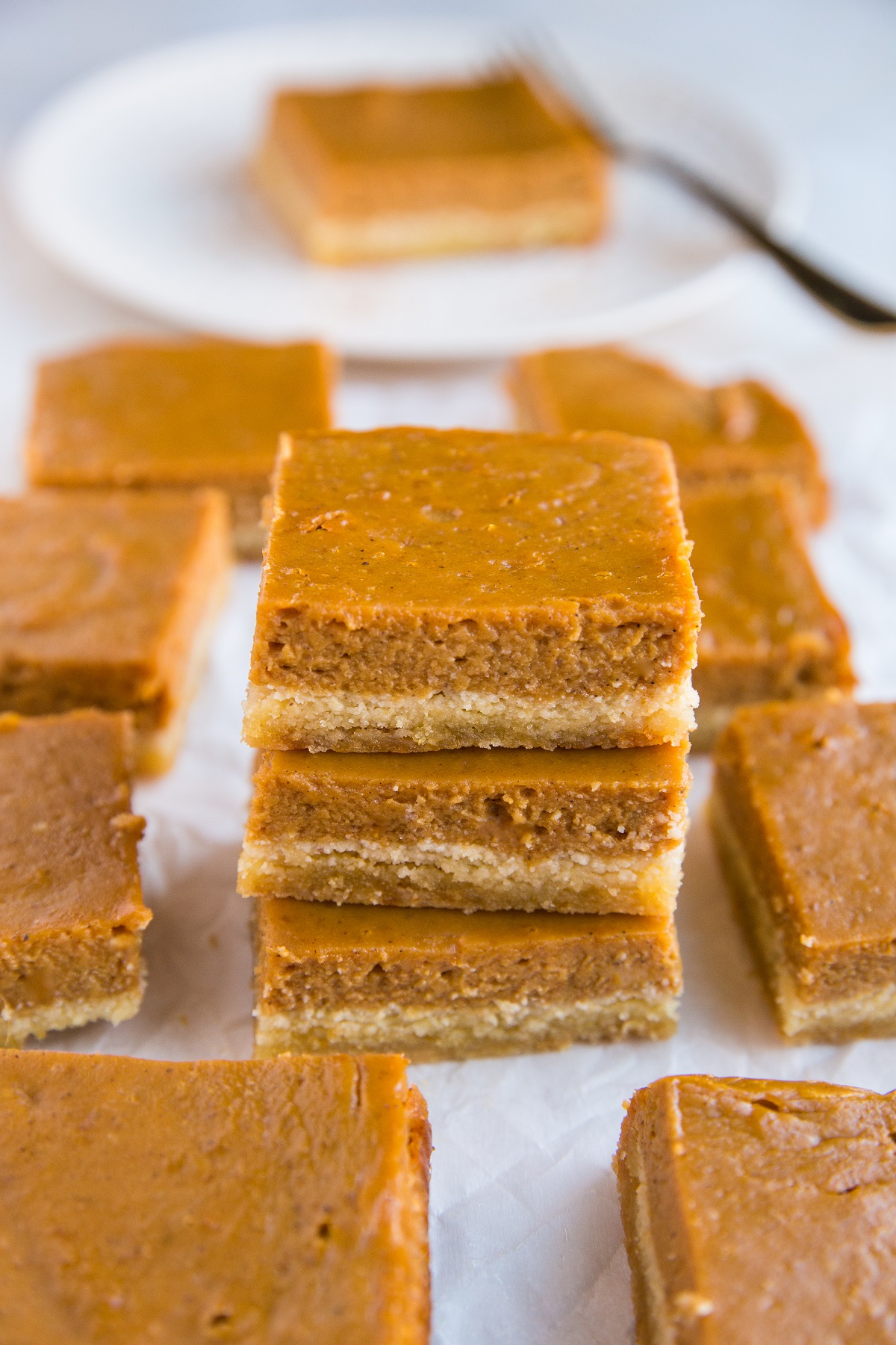 Stack of gluten-free pumpkin pie bars on a sheet of parchment paper.