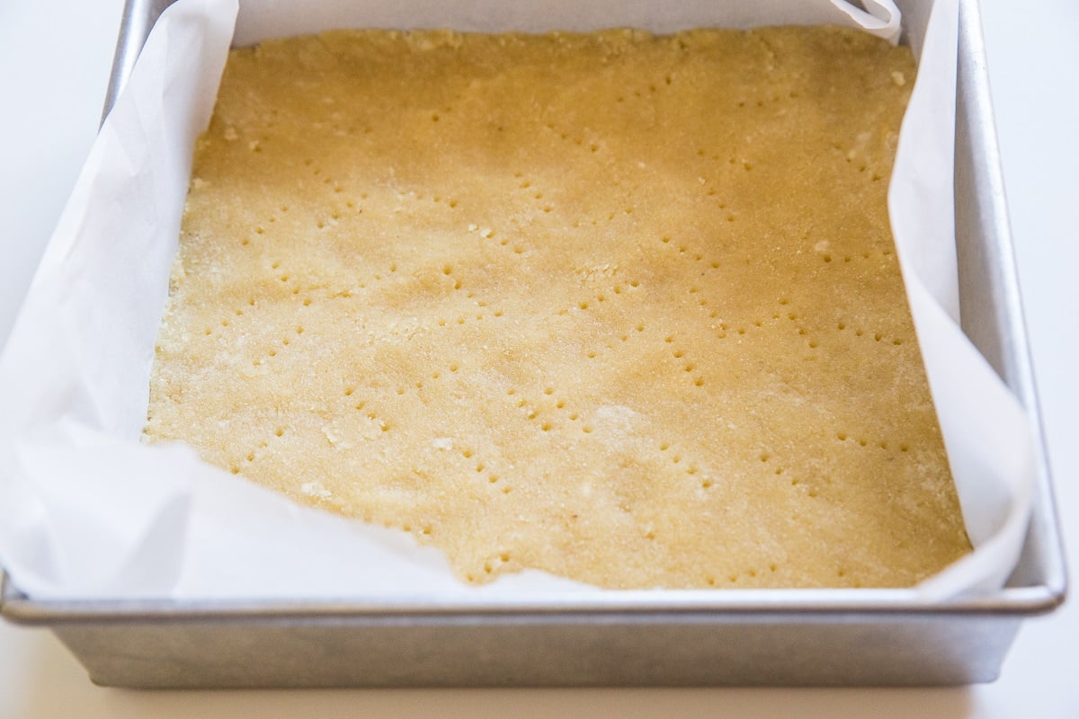 Almond flour crust in a square baking pan to make pumpkin pie bars.