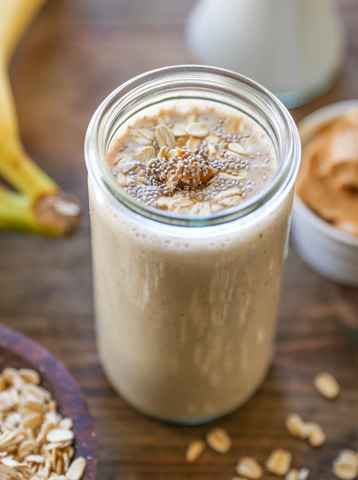 Peanut Butter Banana Oat Protein smoothie in a glass with peanut butter, oats, and chia seeds on top. Ready to drink.