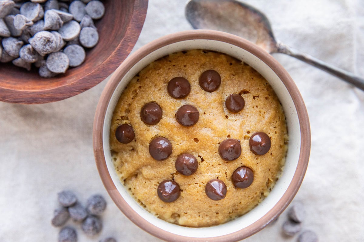 Peanut butter cookie in a mug with chocolate chips on top.