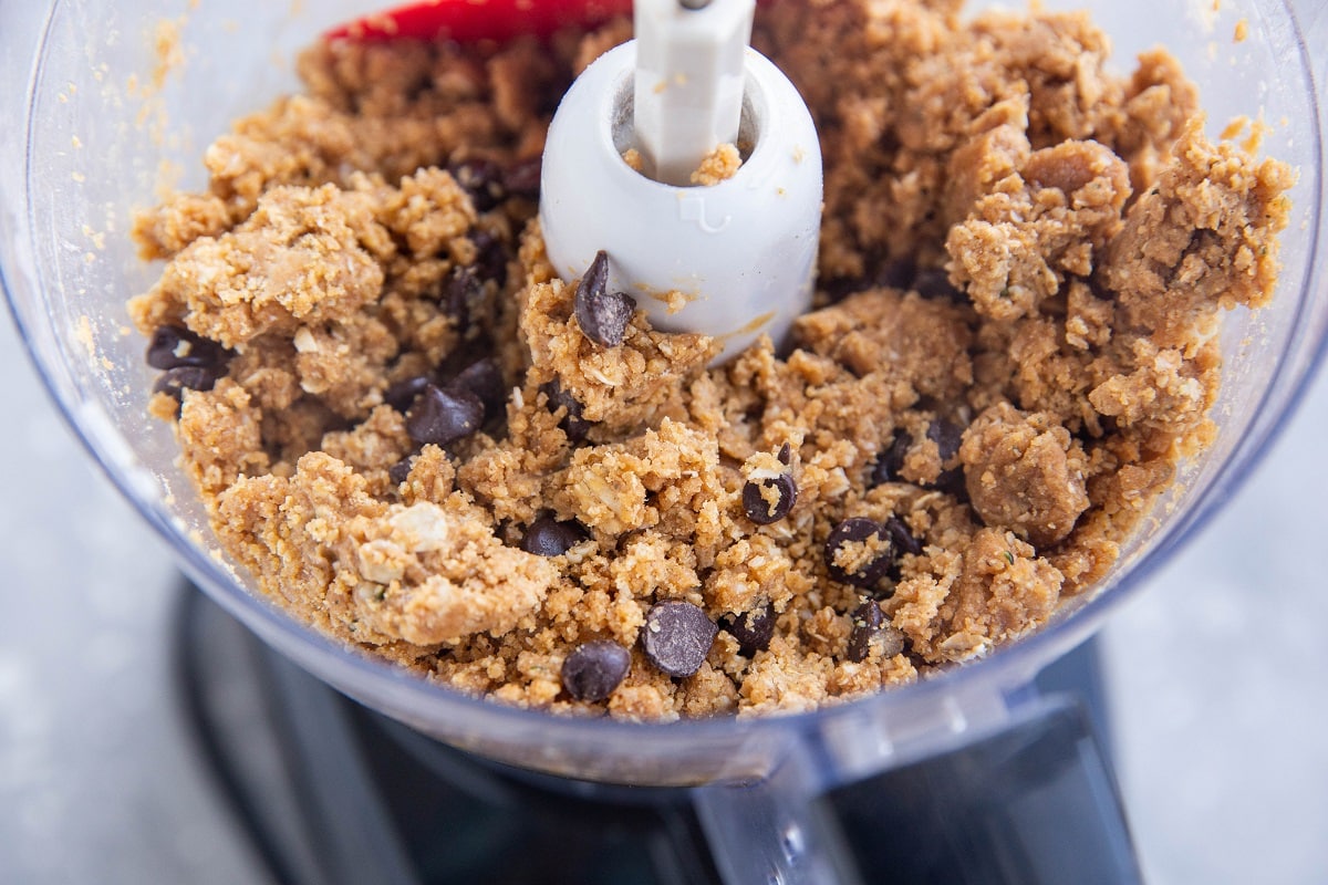 Peanut butter oatmeal protein bite mixture in a food processor, ready to be formed into balls.