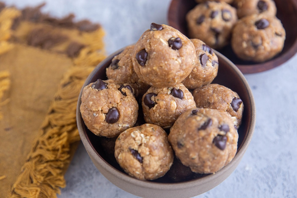 Protein bites in a brown bowl with a golden napkin to the side.