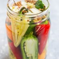 A jar of pickled peppers with jalapeno peppers, habaneros, white peppers, red chiles, etc. Ready to be stored for canning.