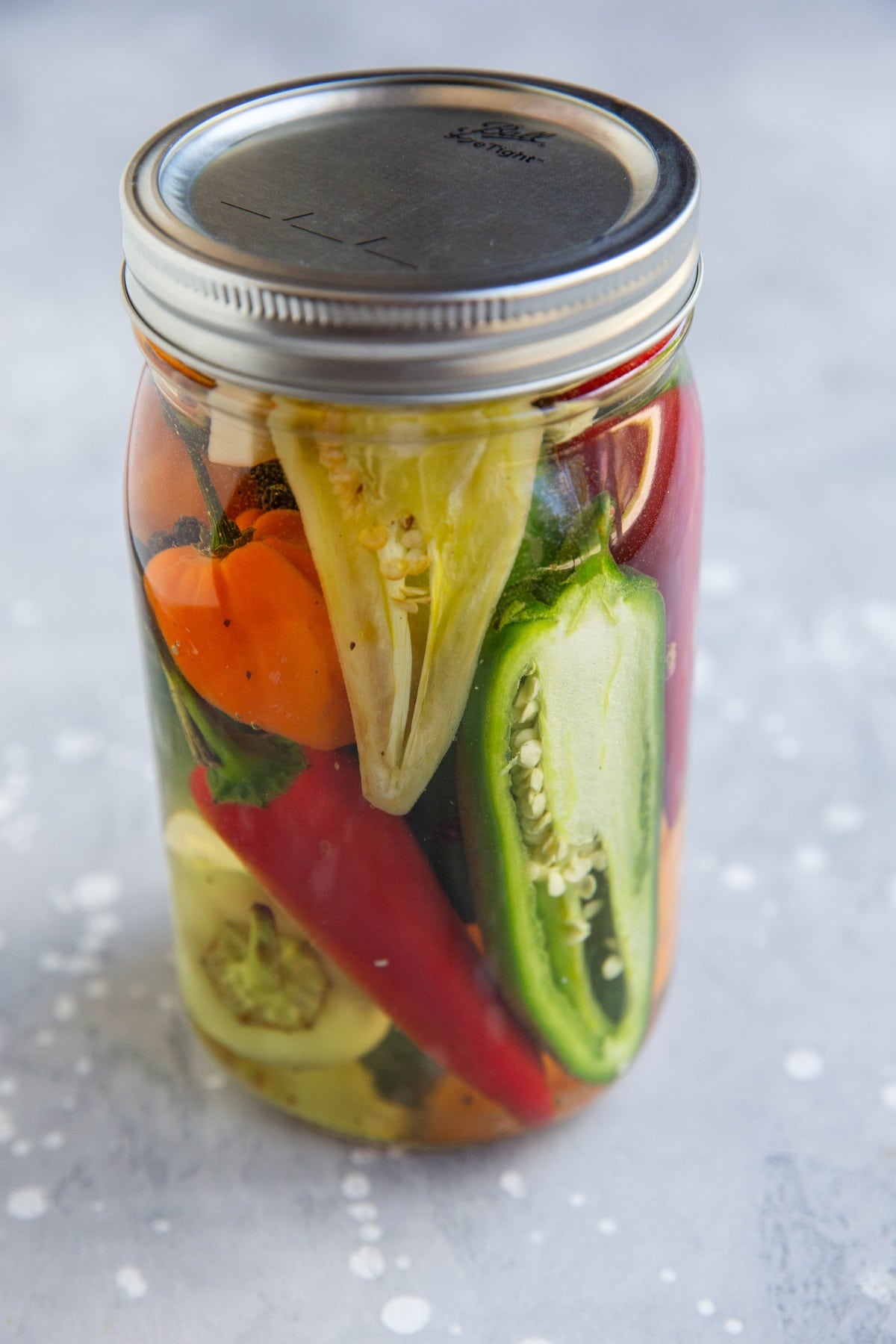 Jar of pickled peppers, ready to be preserved.