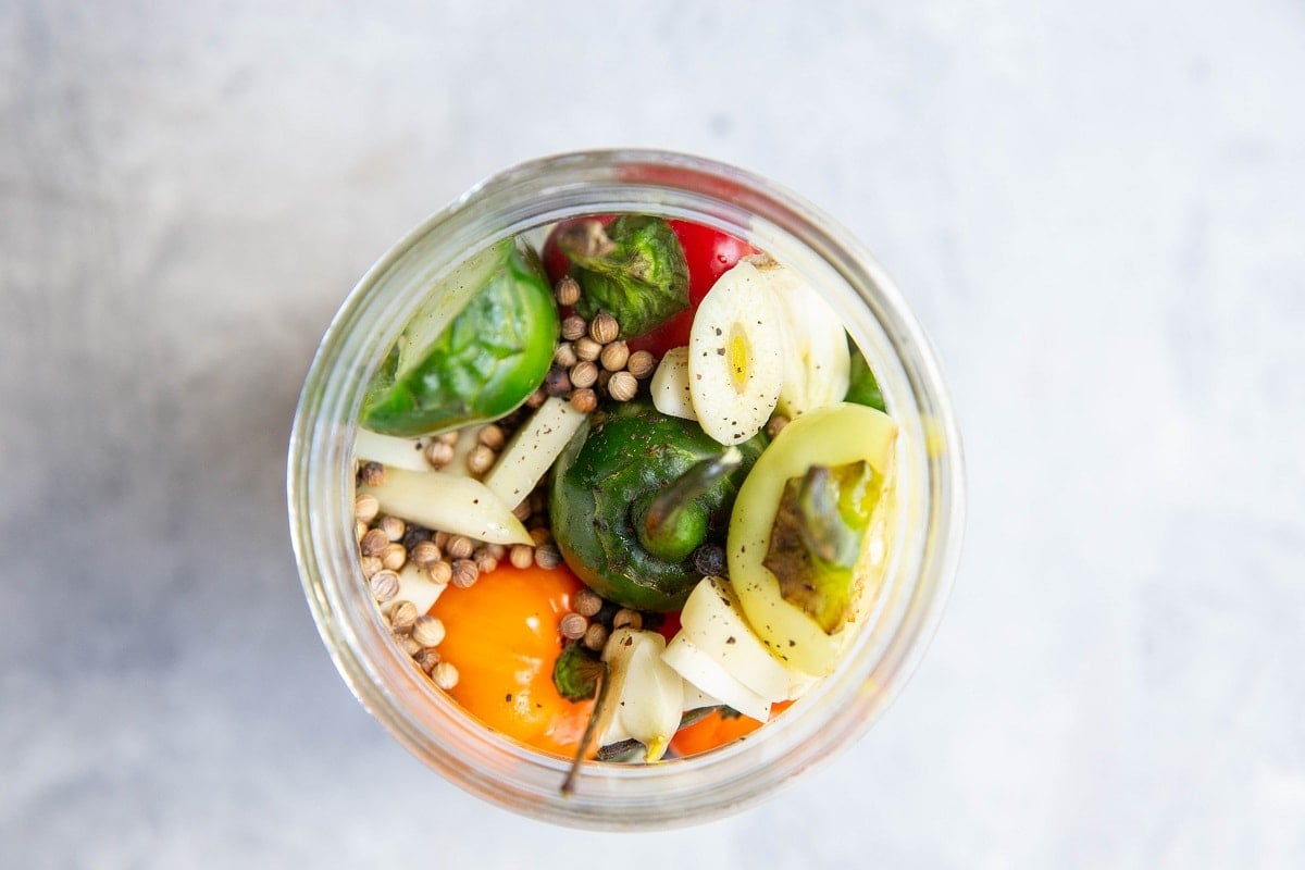 Peppers in a jar with pickling spices and fresh garlic to make quick pickled peppers