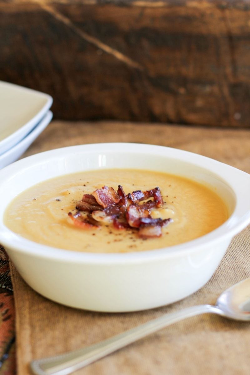 Bowl of cauliflower soup with crispy bacon on top.