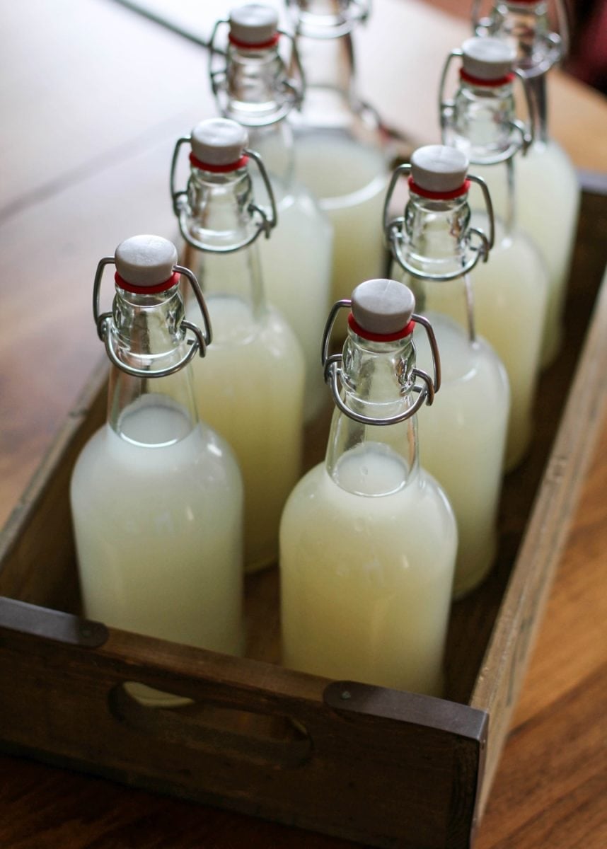 Wooden serving tray with eight bottles of ginger beer inside on a wood table
