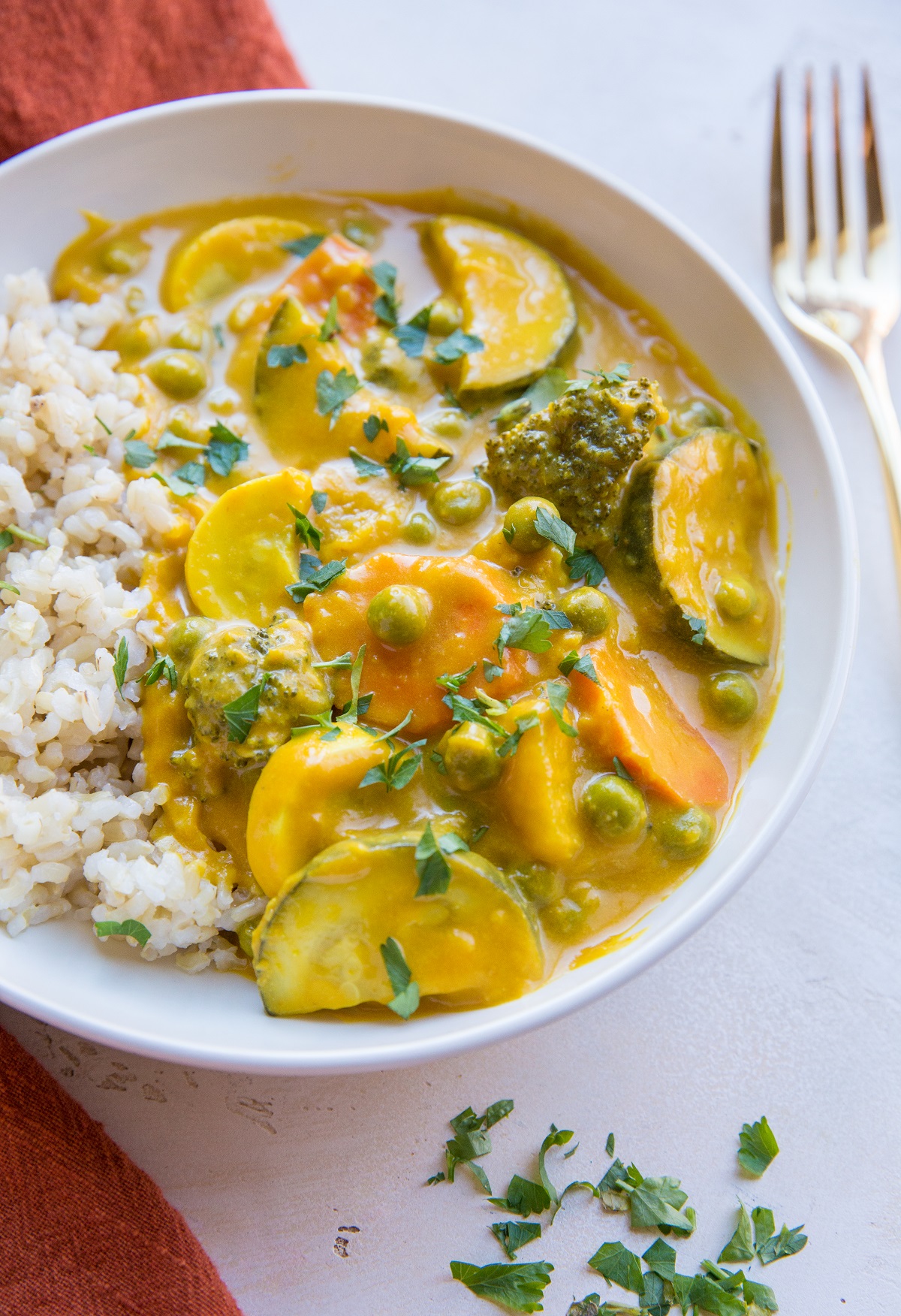 Vegan Pumpkin Curry in a white bowl with rice and cilantro sprinkled all around.