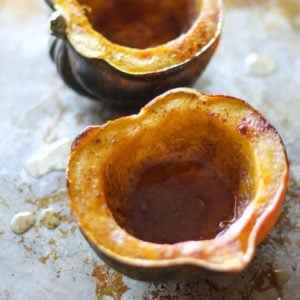 Two acorn squash halves sitting on a baking sheet.