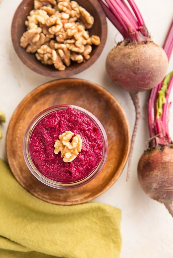 Roasted Beet Pesto sauce in a jar with a walnut on top, ready to serve.