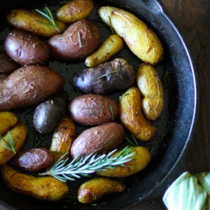 Rosemary Roasted Fingerling Potatoes in a cast iron skillet with fresh rosemary all around.