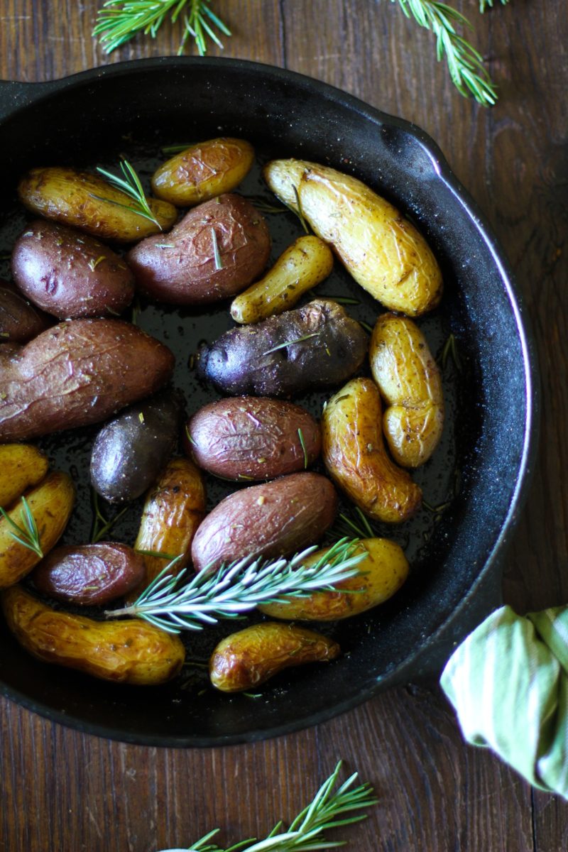Rosemary Roasted Fingerling Potatoes in a cast iron skillet with fresh rosemary all around.
