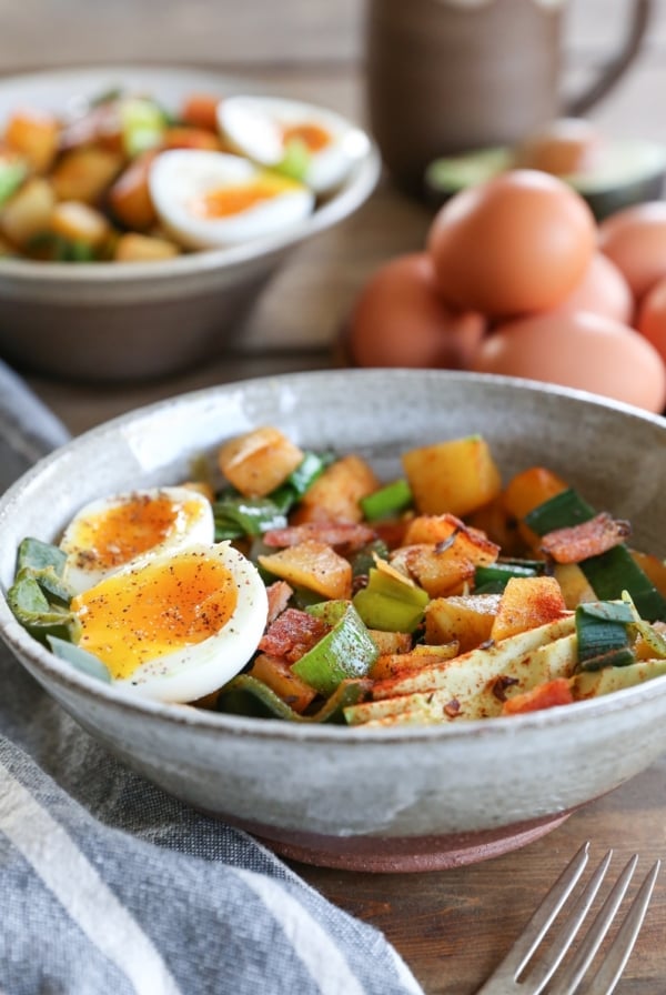 large ceramic bowl full of rutabaga hash with a 6-minute jammy egg on top and a fork to the side. Ready to eat for breakfast.