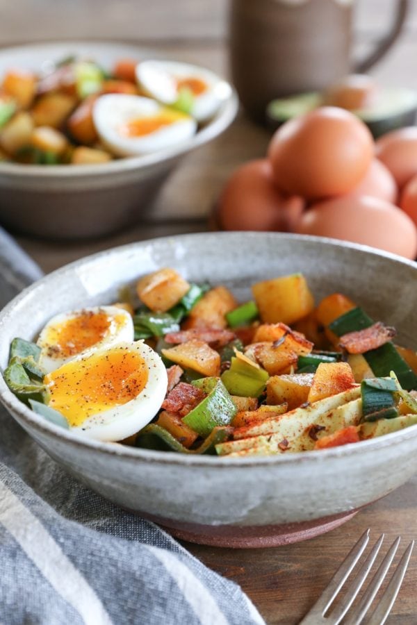 large ceramic bowl full of rutabaga hash with a 6-minute jammy egg on top and a fork to the side. Ready to eat for breakfast.