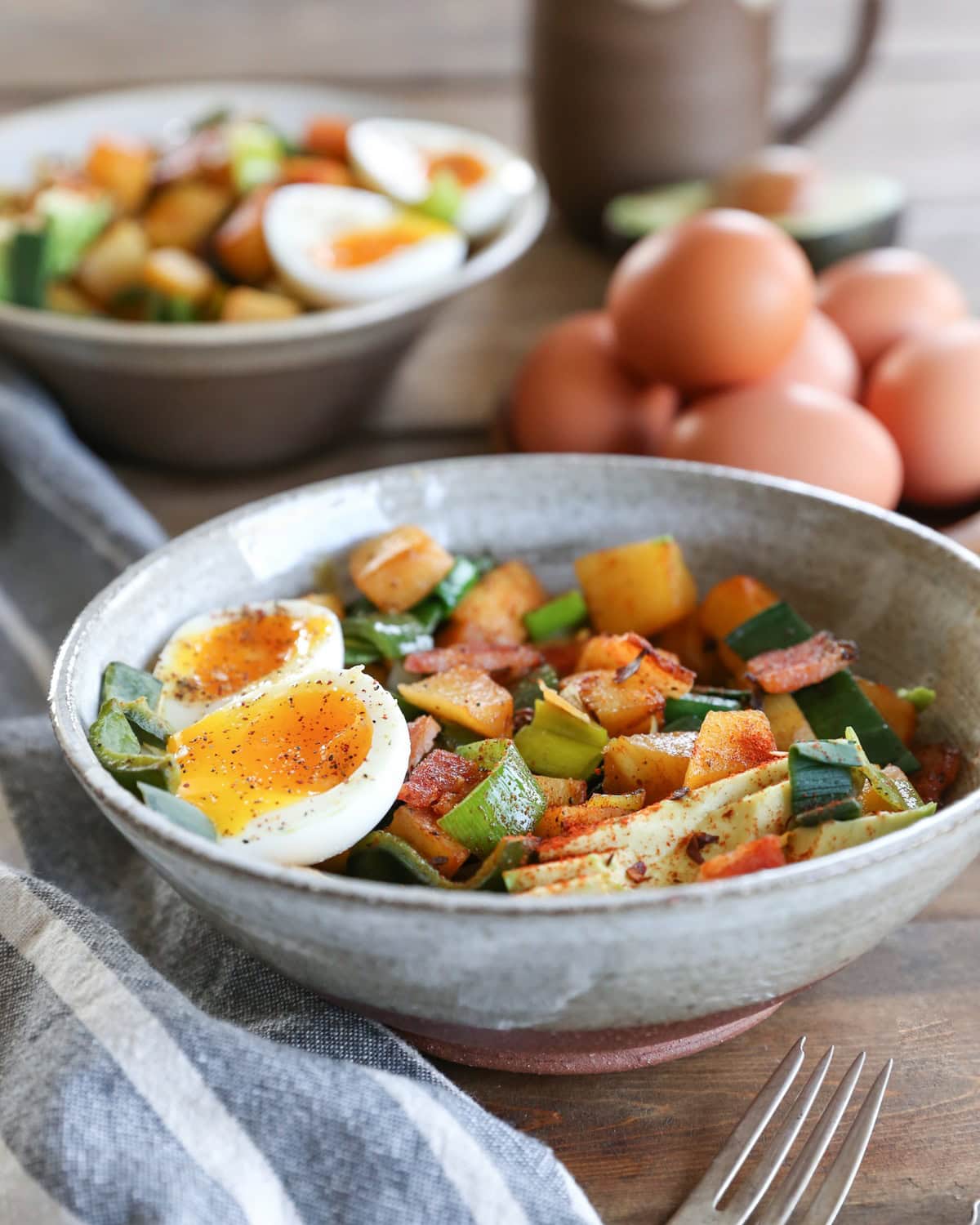large ceramic bowl full of rutabaga hash with a 6-minute jammy egg on top and a fork to the side. Ready to eat for breakfast.