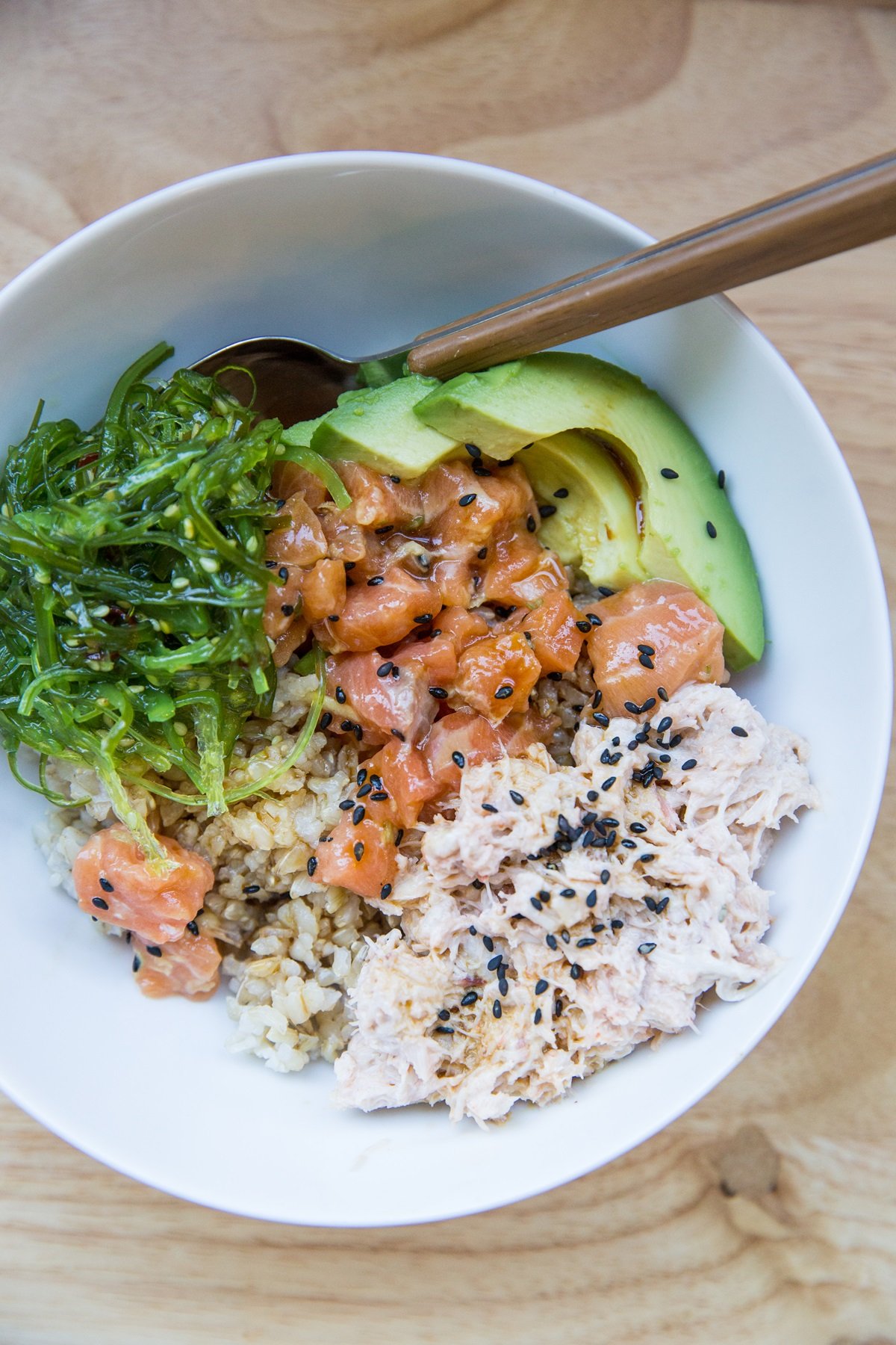 Salmon Poke Bowl with salmon poke, brown rice, crab salad, seaweed salad and avocado