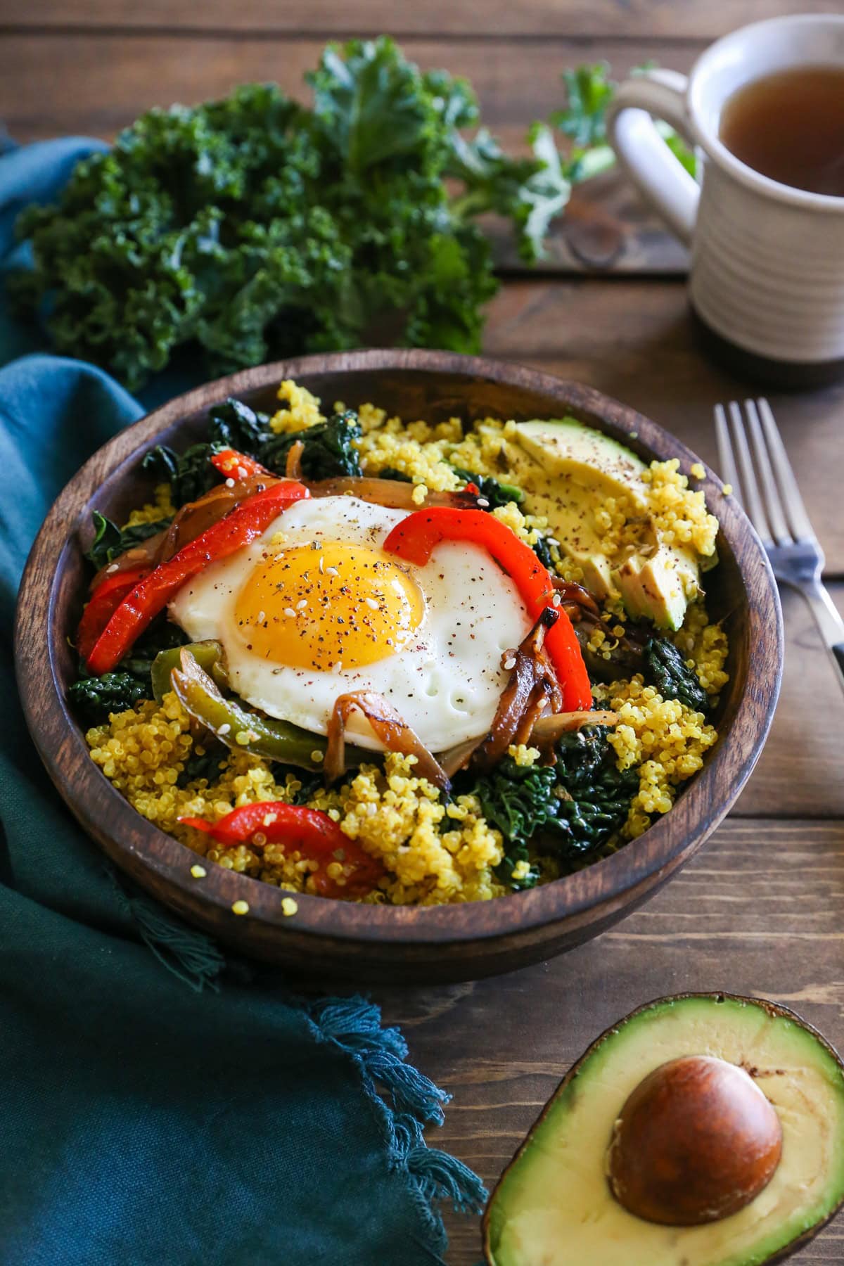 Turmeric quinoa with sauteed onions, peppers, and a sunny side up egg with half an avocado to the side.