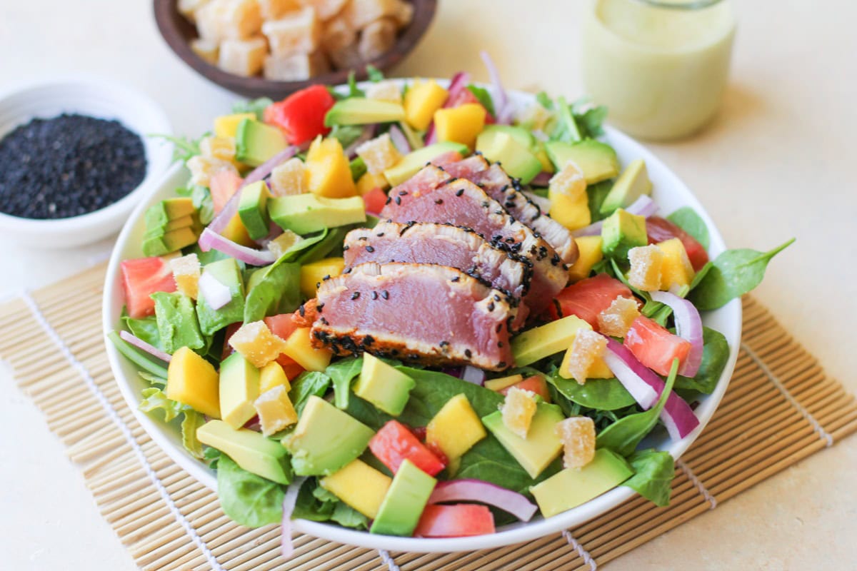 Big white bowl full of salad with seared ahi on top. Ready to serve.