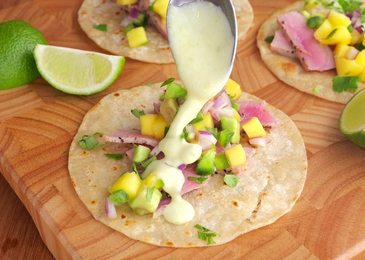 Fish taco with wasabi sauce being drizzled on top.