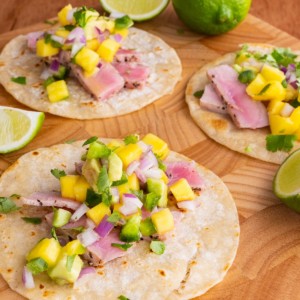 Seared Ahi Tacos with Mango Avocado Salsa on a wooden cutting board, ready to eat.