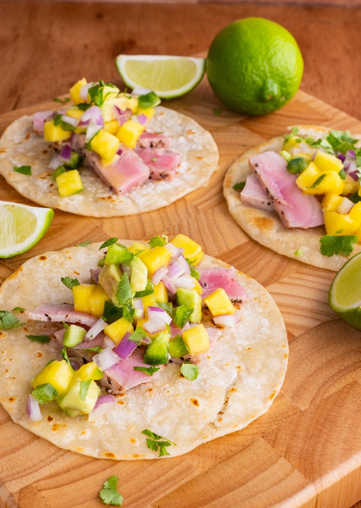 Seared Ahi Tacos with Mango Avocado Salsa on a wooden cutting board, ready to eat.