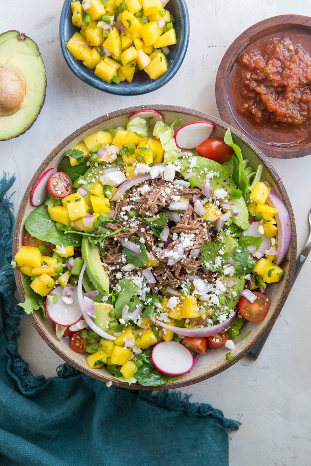 Shredded Beef Taco Salad with spring greens, avocado, cherry tomatoes, mango salsa, and more! A fresh and filling salad recipe!