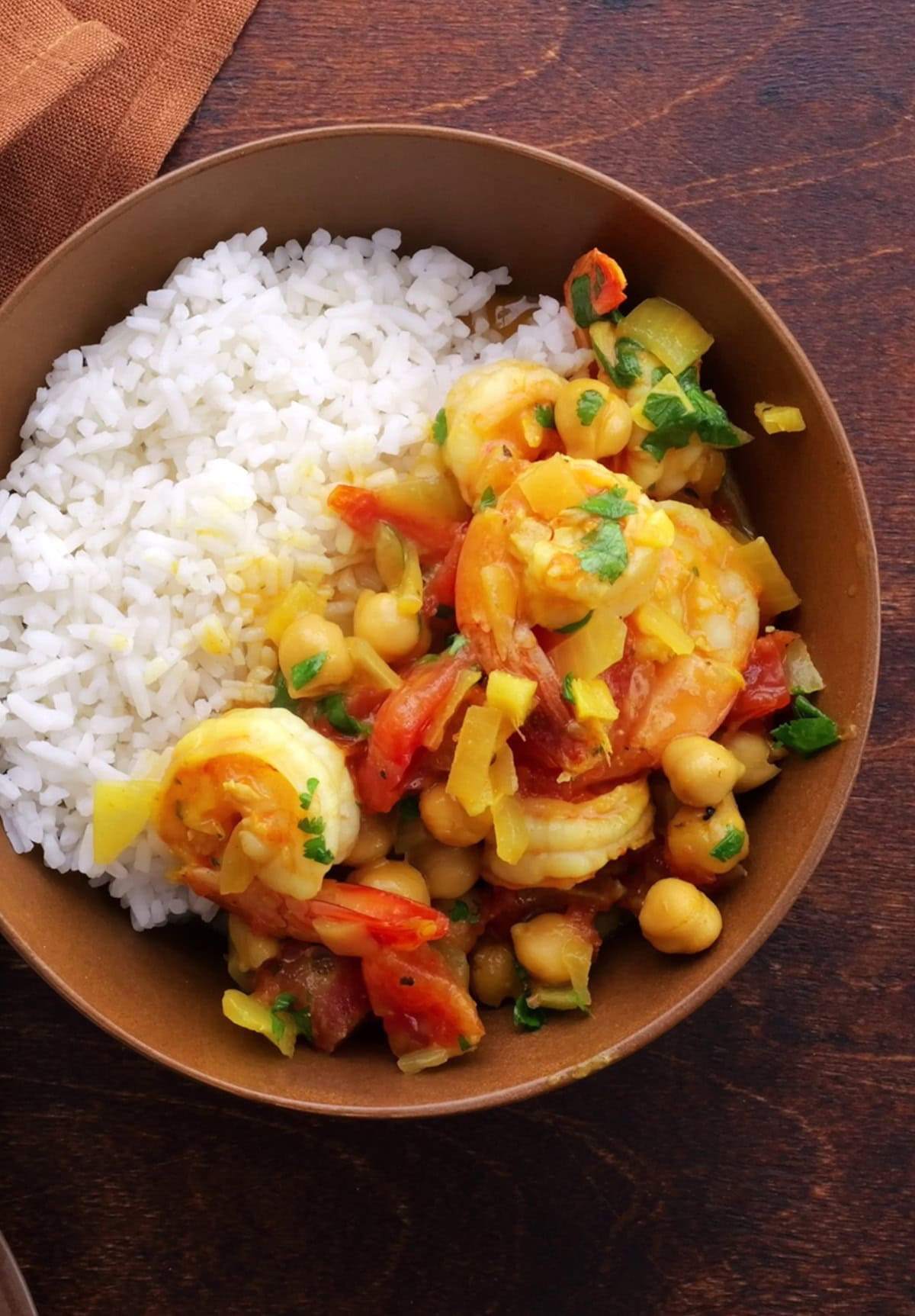 Big brown bowl of coconut shrimp curry with white rice and a bowl of white rice to the side