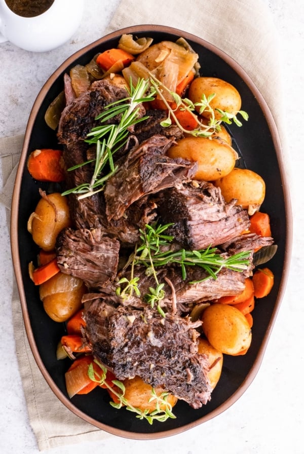 Platter of shredded beef on top of potatoes, carrots, and onions, ready to serve.