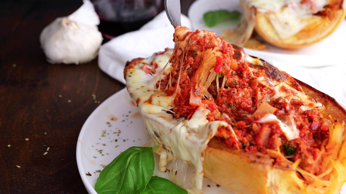 Spaghetti squash on a plate with red sauce and a fork taking a bite.