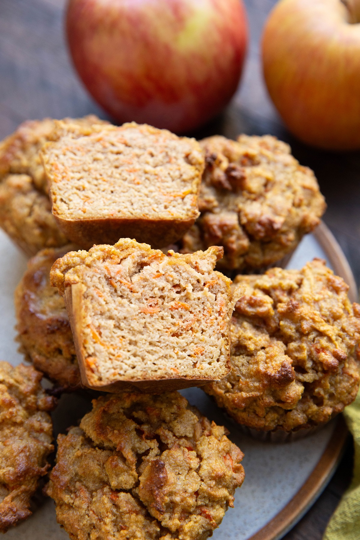 Plate of apple carrot muffins with one sliced in half so you can see the moist inside.