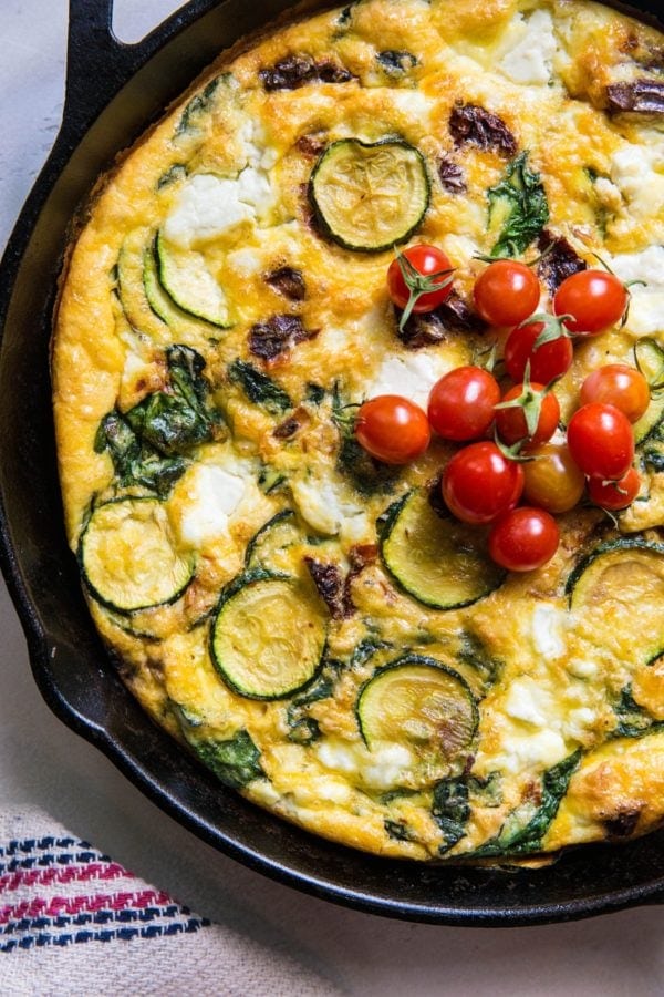 Spinach Frittata with Zucchini, Sun-Dried Tomatoes, and Goat Cheese in a cast iron skillet.