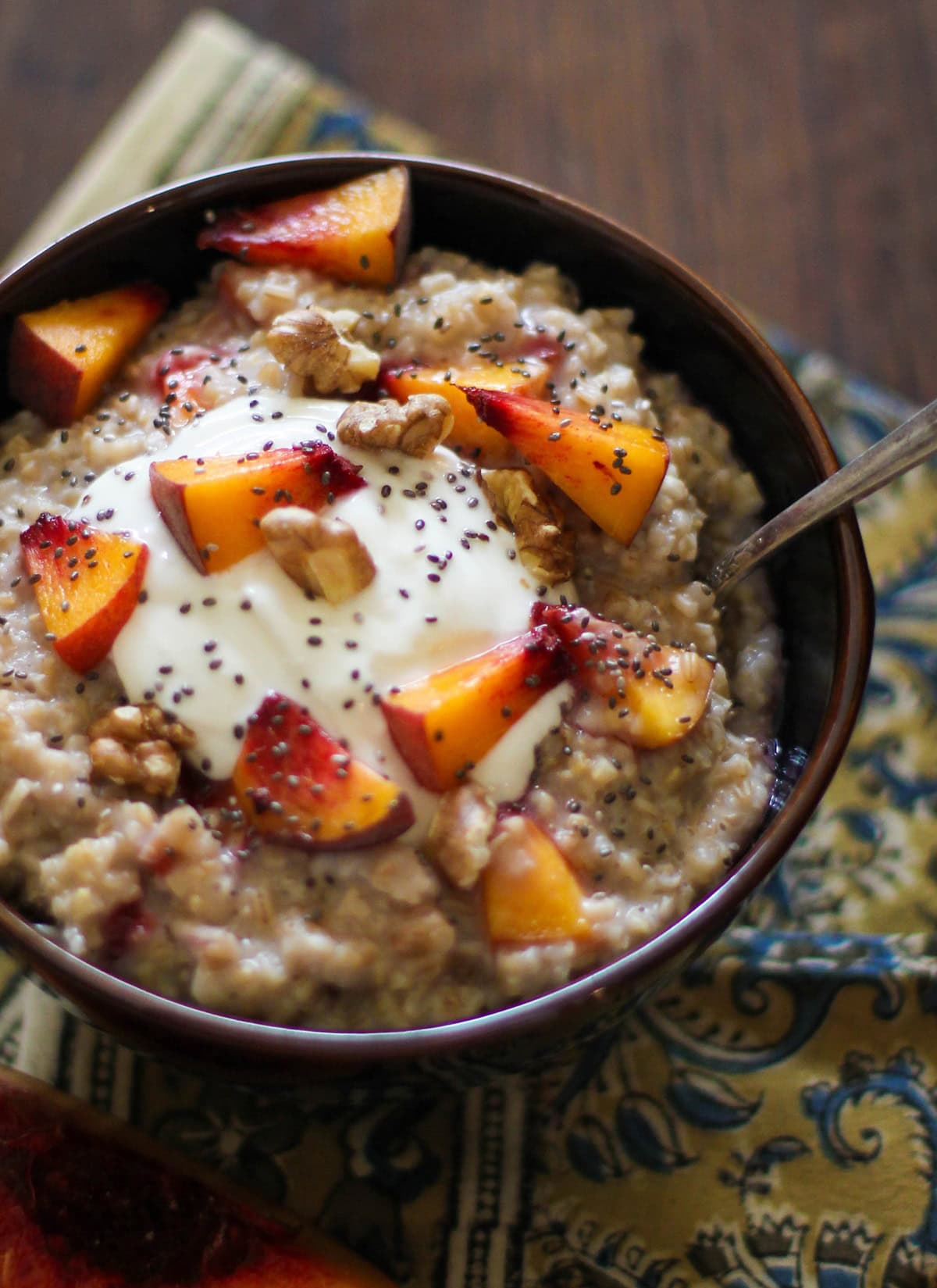 Bowl full of oatmeal with chia seeds, walnuts, and chopped peaches.