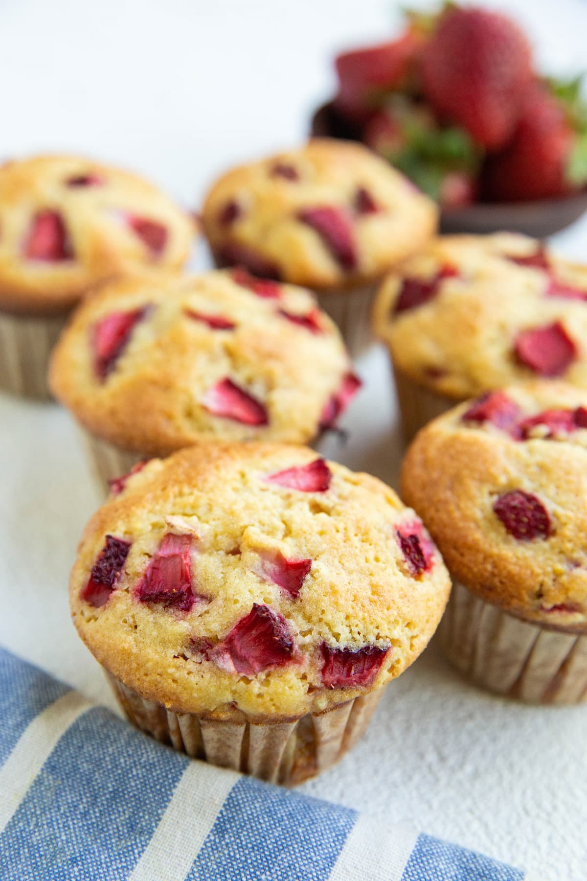 Freshly baked strawberry muffins on a white background with a blue napkin