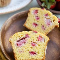 One strawberry muffin sliced in half on a small plate so you can see the moist inside.