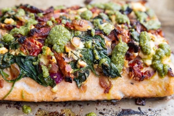 Baked salmon with feta, sun-dried tomatoes, onion, spinach and pesto sauce on top, fresh out of the oven.