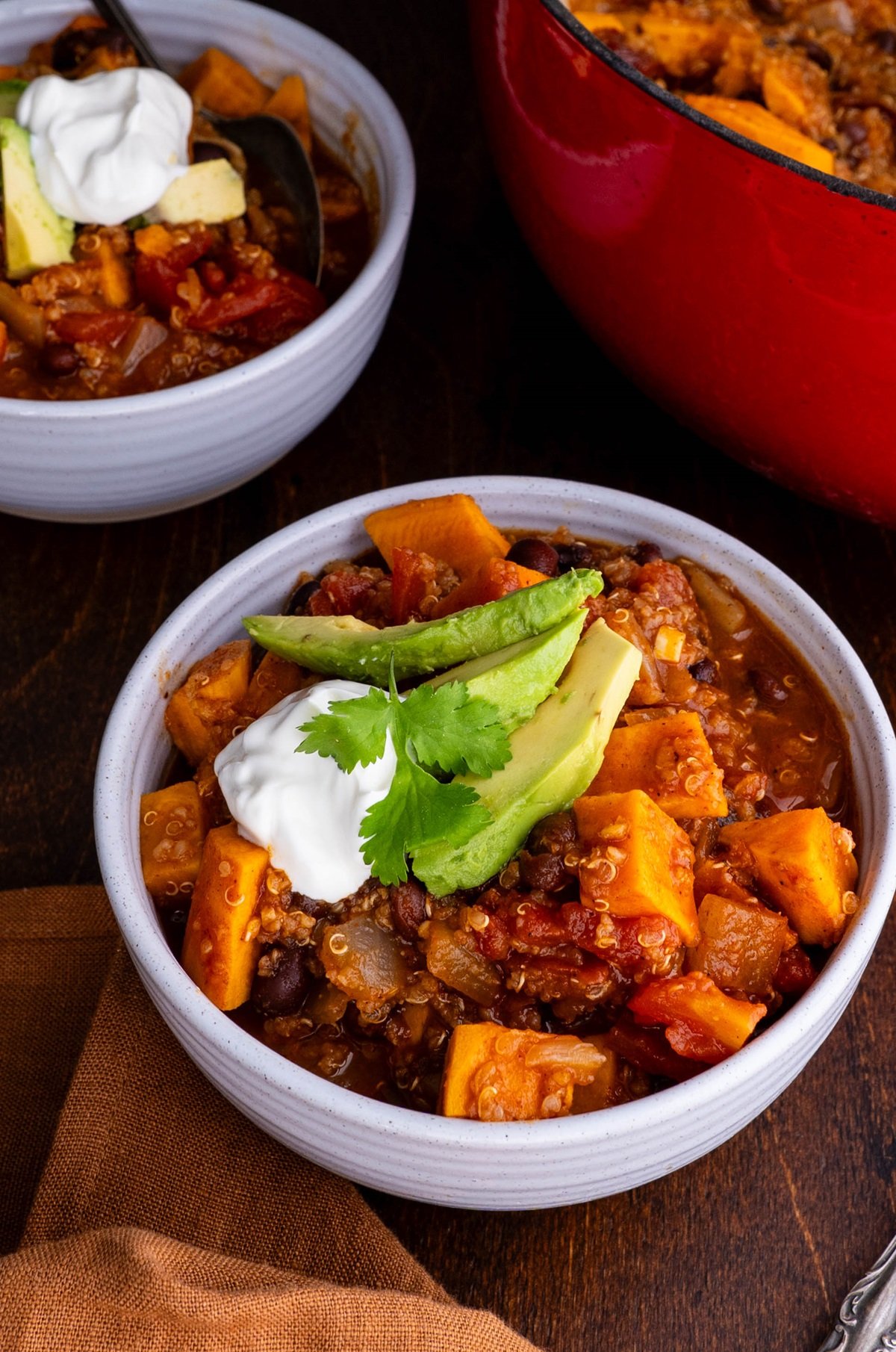 Two bowls of Sweet Potato Black Bean and Quinoa Chili topped with avocado and sour cream