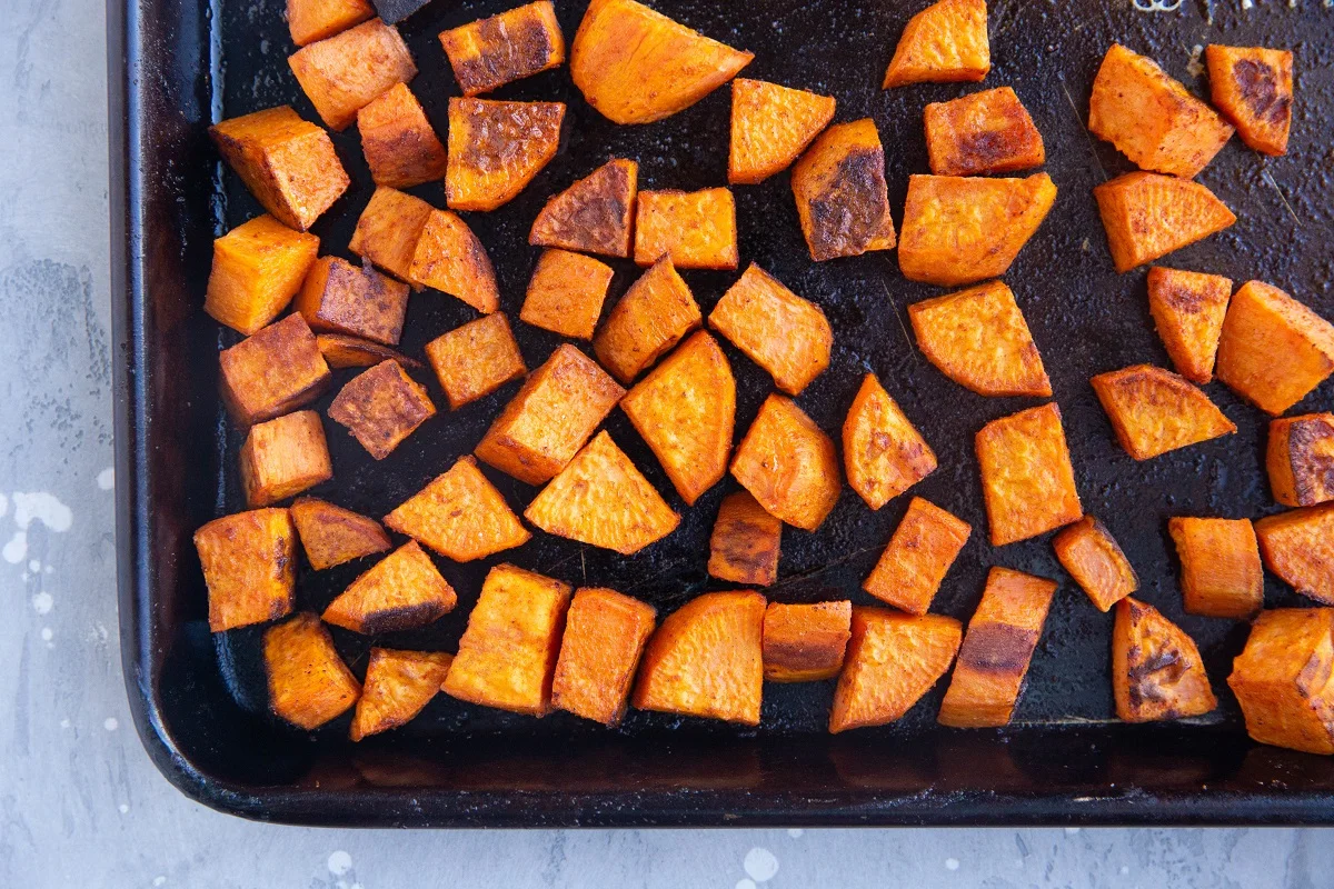 Roasted chunks of sweet potatoes on a baking sheet, fresh out of the oven.