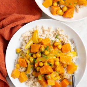 Butternut Squash and Yam Curry in a white bowl with a wood inlay fork and a red napkin to the side.