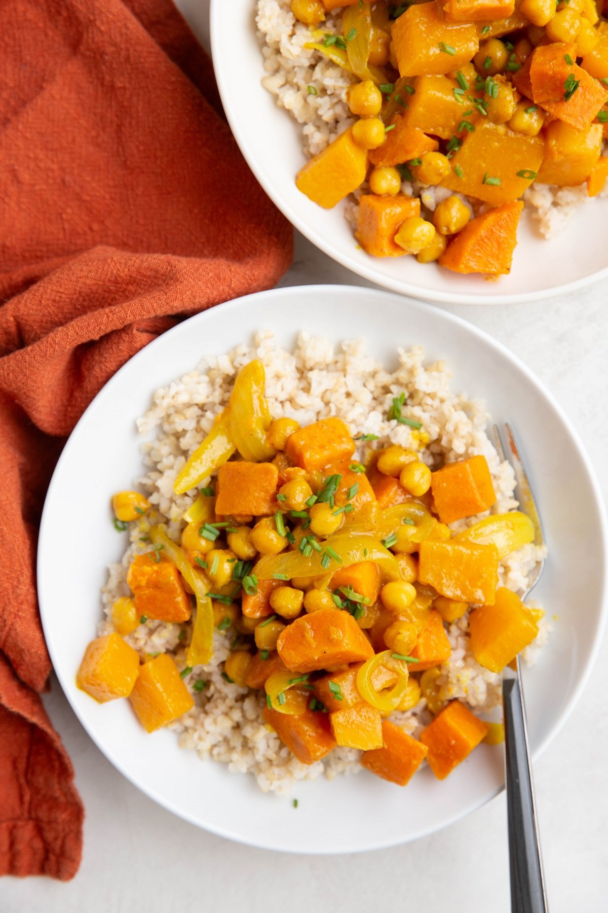 Butternut Squash and Yam Curry in a white bowl with a wood inlay fork and a red napkin to the side.