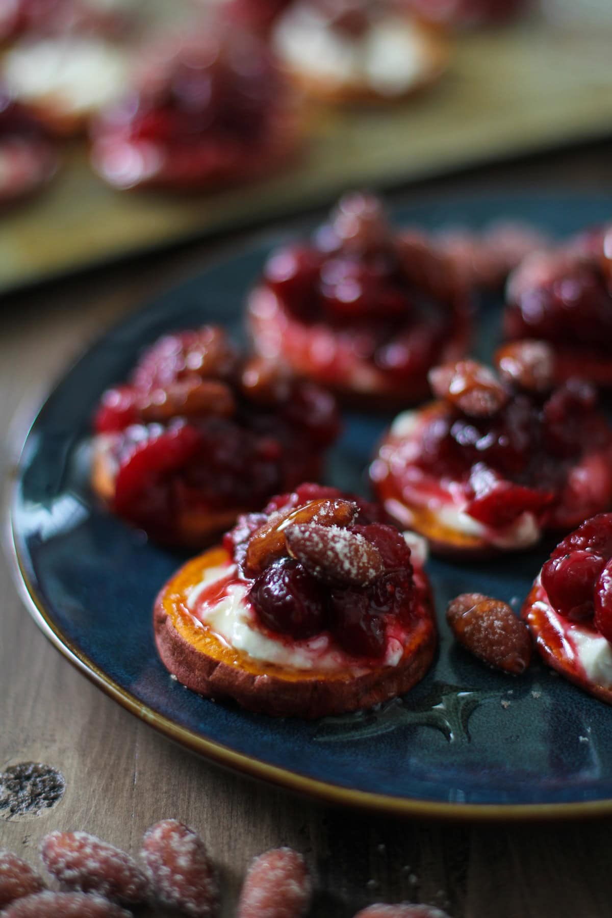 Blue plate of Sweet Potato Rounds with Goat Cheese, Roasted Cranberries, ready to serve as an appetizer.