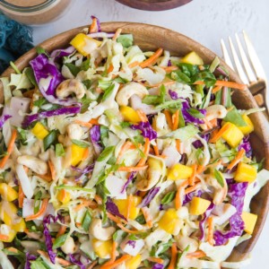 Wooden bowl full of chopped salad with cabbage, chicken and peanut dressing.