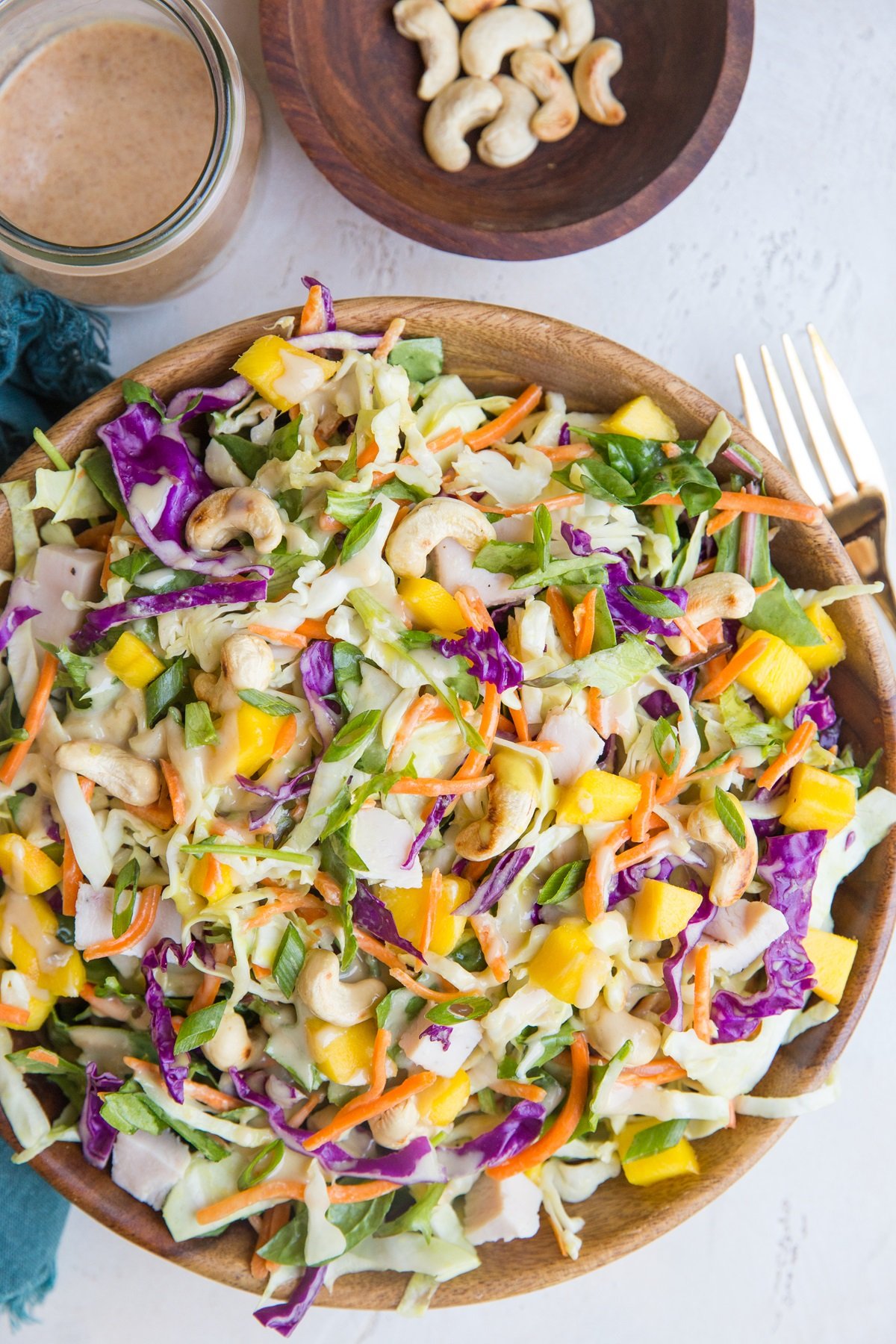 Wooden bowl full of chopped salad with cabbage, chicken and peanut dressing.