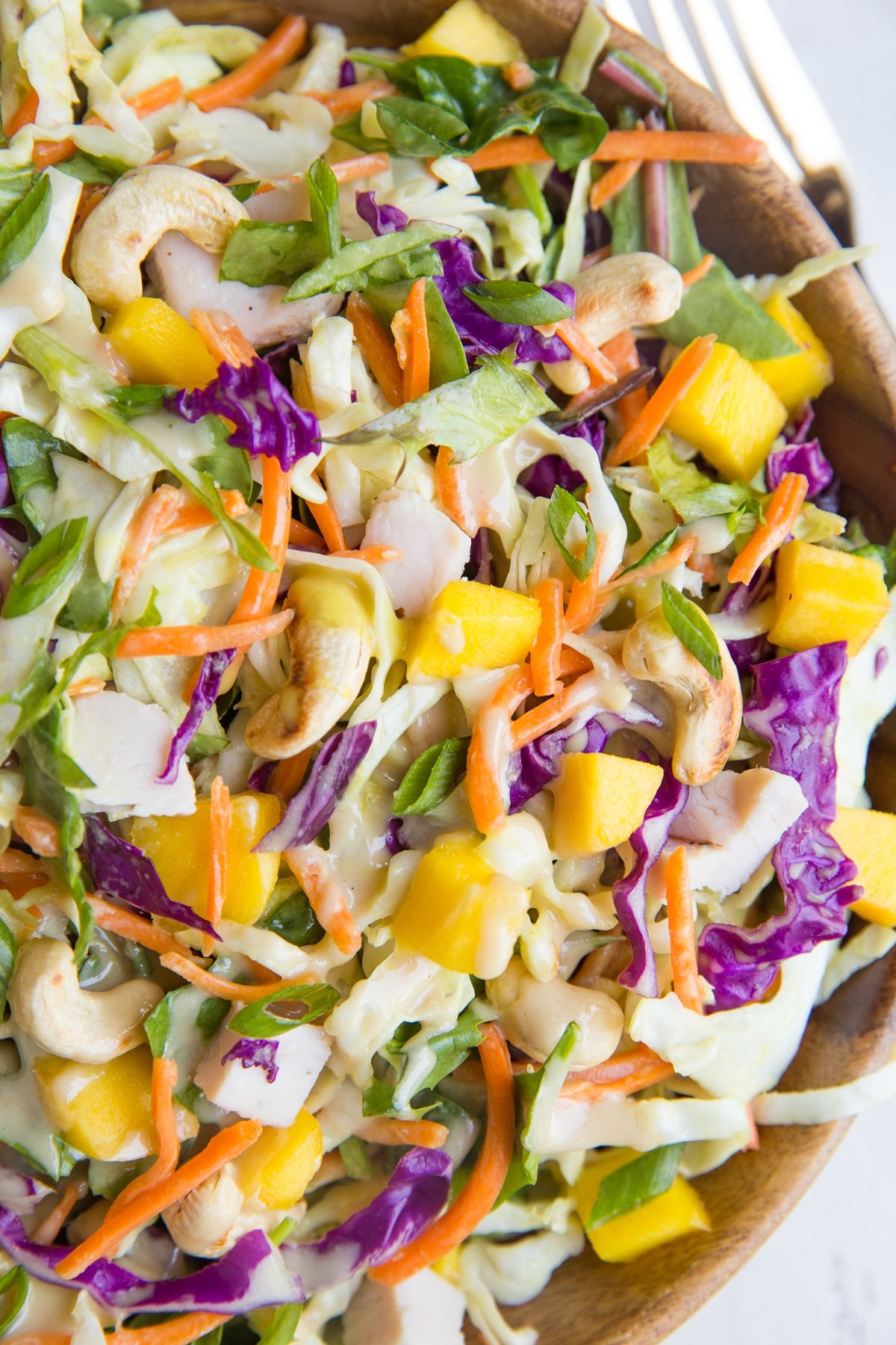Thai Chicken Chopped Salad with cabbage, mango, and peanut dressing in a wooden bowl, ready to serve.